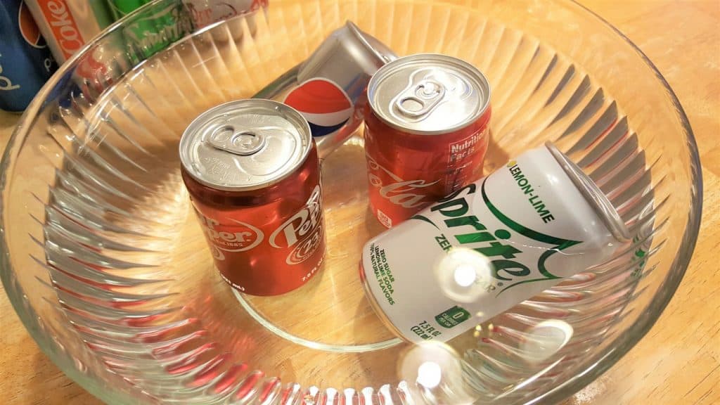 four drink cans in the bowl of water with 2 floating and 2 not floating