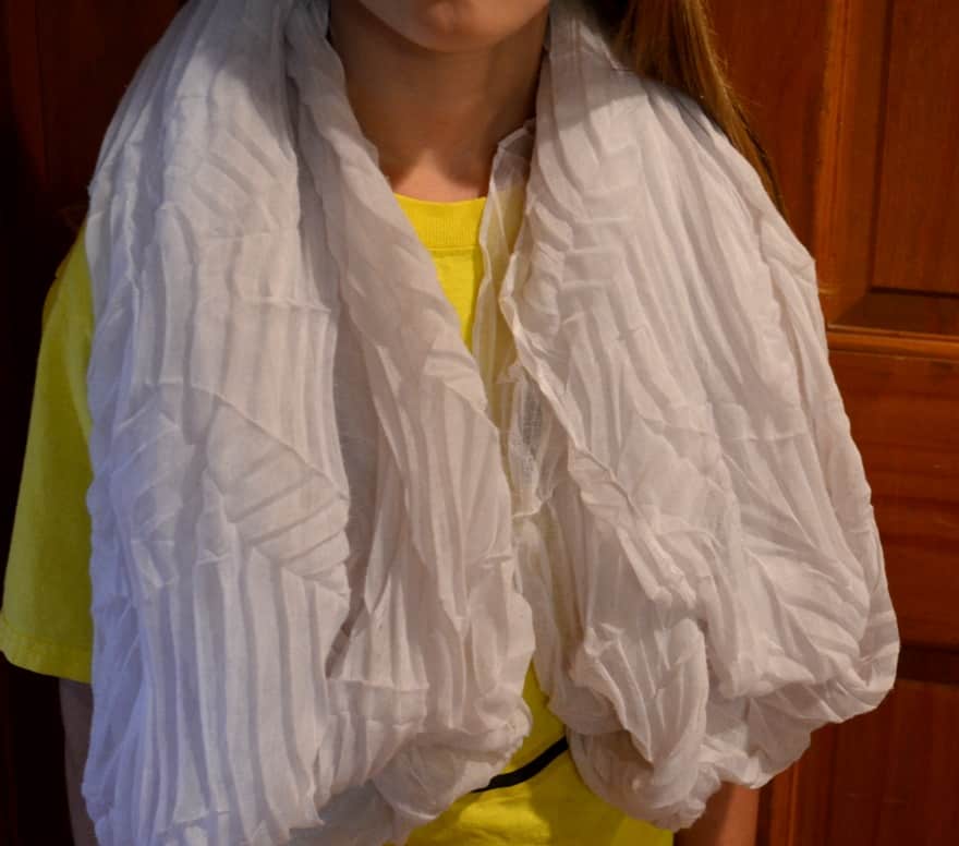 Child with white scarf wrapped around neck and shoulders